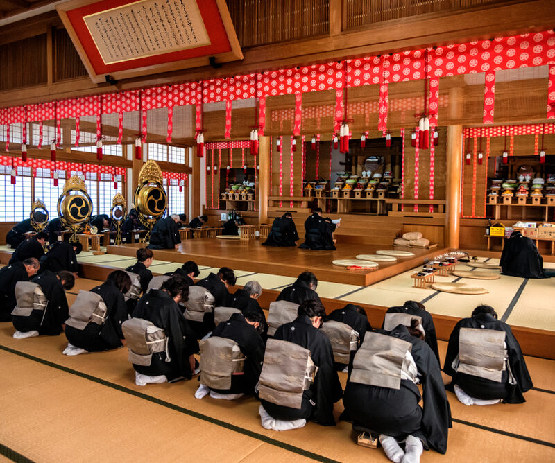 People in traditional attire bow in a Japanese temple during a ceremonial ritual