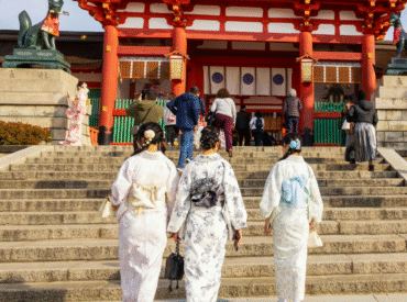 Visitors in traditional kimonos walking up steps to a Japanese shrine