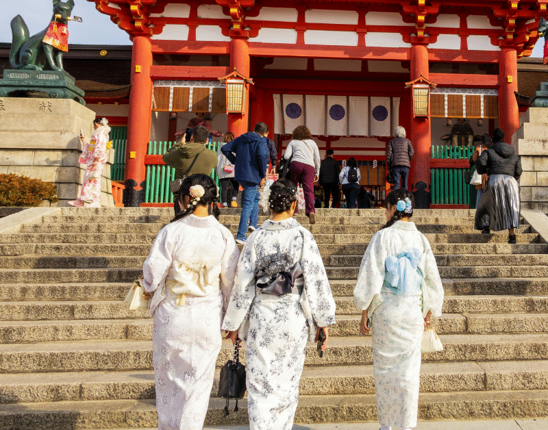 Visitors in traditional kimonos walking up steps to a Japanese shrine