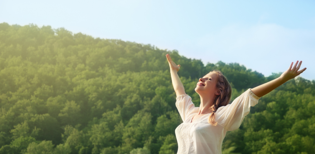Woman raising arms in nature expressing gratitude and freedom