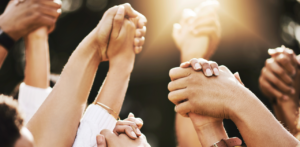 Group of diverse people holding hands in unity, representing community support, teamwork, and togetherness